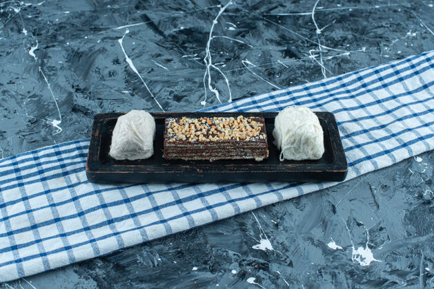 美味棉花糖和巧克力华夫饼放在茶巾上的木盘上 蓝色背景脆风味美味