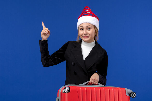 工作正面图年轻女子背着红包上蓝墙度假游女子度假圣诞节职业人