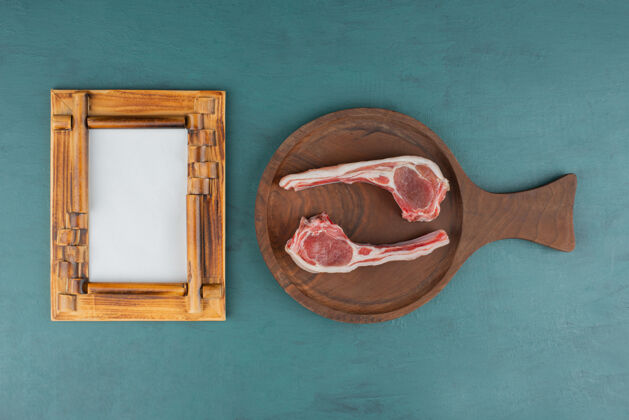 肉生羊排放在有画框的木板上木头木板顶视图