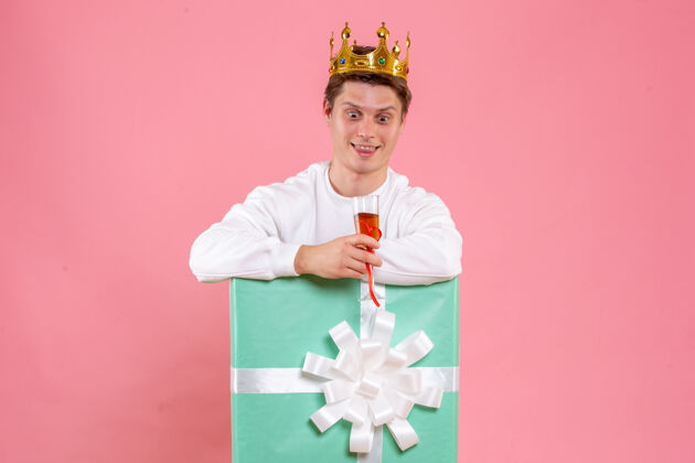 风景正面图：年轻男性 戴着皇冠 一杯酒 背景为粉色情感圣诞皇冠