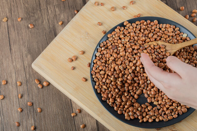 素食木桌上放着一个黑盘子 上面放着生的棕色芸豆堆棕色营养