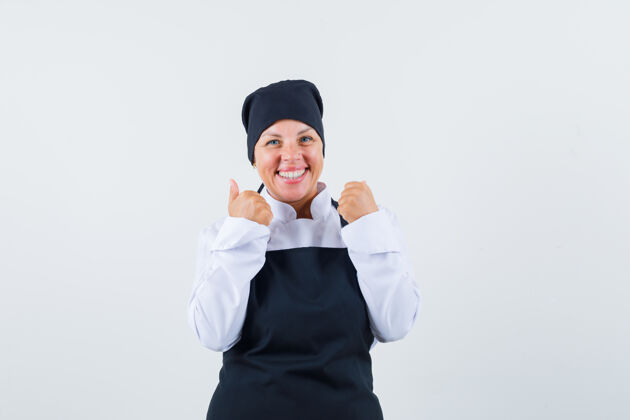 健康穿着黑色厨师制服的金发女人握紧拳头 看起来很漂亮化妆烹饪清洁