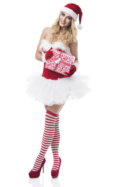 微笑穿着圣诞老人服装的性感女人在白墙上摆姿势时装模特高跟鞋新鲜