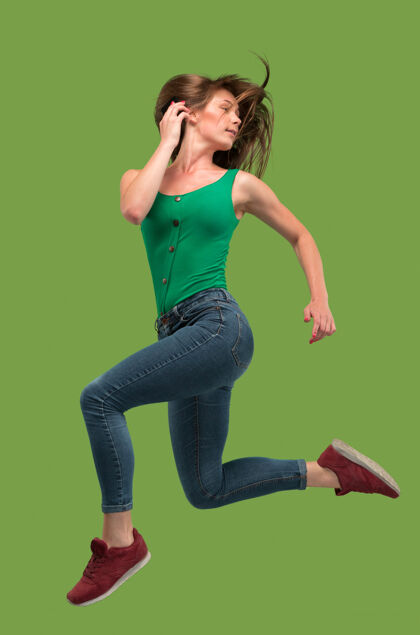 运动在移动的自由相当快乐的年轻女子跳跃和对橙色工作室的手势半空中拍摄情绪自由年轻