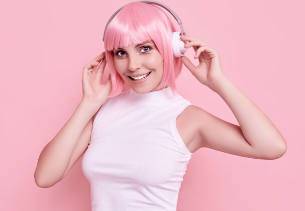 声音粉红头发的美女肖像在耳机里欣赏音乐时尚音频美女