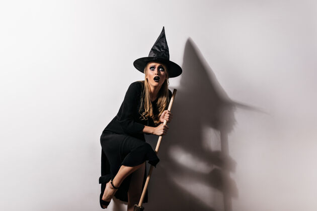 神秘手持魔法扫帚的受惊女巫万圣节受惊女巫扮相的室内照片万圣节服装扫帚