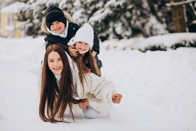 哥哥妈妈带着女儿和儿子在满是雪的公园里玩家庭女孩女儿