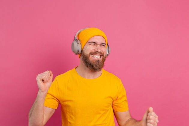 手势帅哥带着粉色背景上的耳机随意跳舞无线技术人