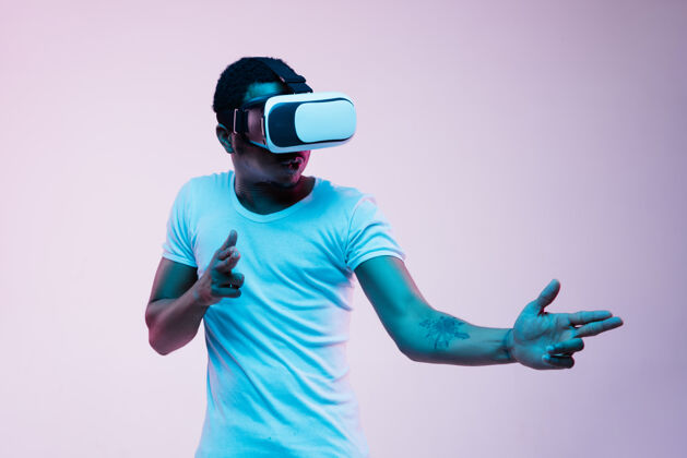 霓虹灯年轻的非洲裔美国男子的指向和使用虚拟现实眼镜霓虹灯梯度背景美国虚拟现实多彩