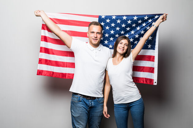 男性一对漂亮的夫妇手里拿着美国国旗 把自己隔离在白色的地面上年轻脸享受