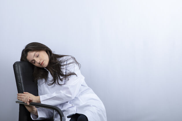 疾病戴着医用面罩和白大褂睡在椅子上的女医生的画像护士流行病肖像