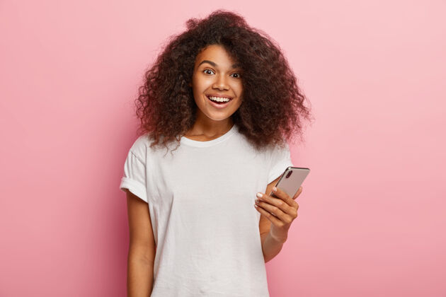 快乐一位穿着休闲服的美籍非洲女性 手持现代智能手机 等待来电 很高兴收到男朋友的留言非洲白色女士