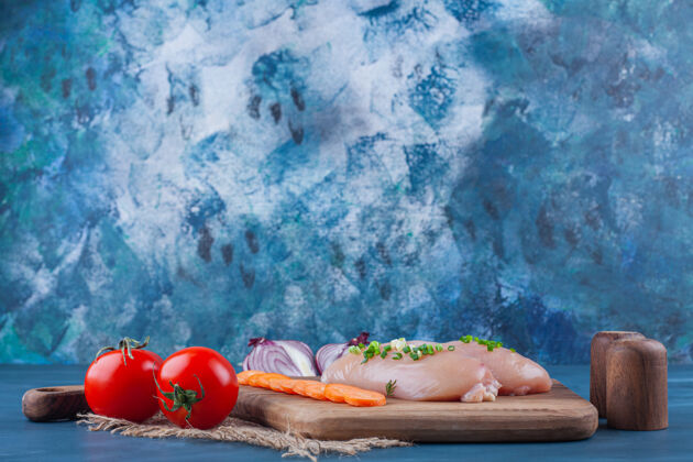 配料鸡胸肉切胡萝卜放在菜板上 旁边是蓝色表面的洋葱片砧板新鲜肉
