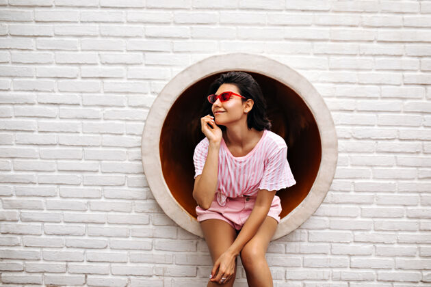 背景时髦的女人在砖墙上摆姿势戴着粉色太阳镜的快乐女人的户外照片乐趣模特户外