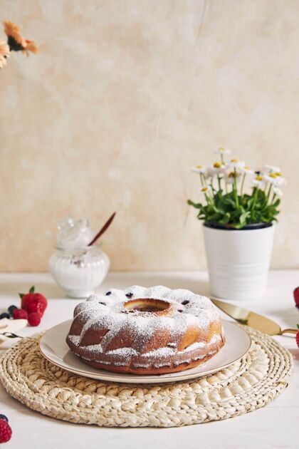 浆果一张白色桌子上放着水果和粉末的环形蛋糕的垂直镜头派花瓶圆形