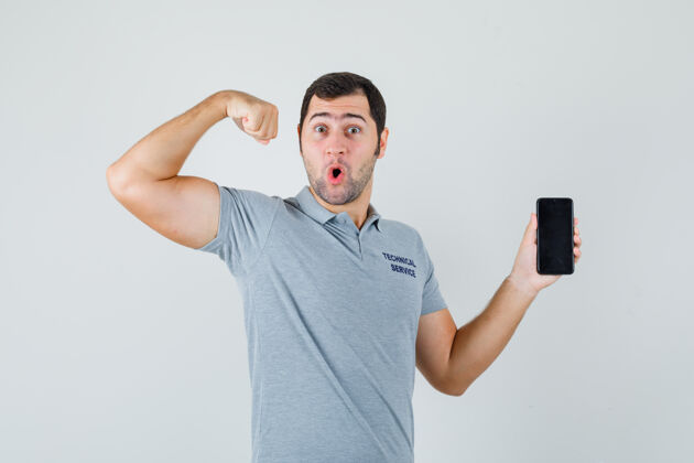 服务器身着灰色制服的年轻技师手持手机 展现肌肉 看上去很自信 前视图肖像数据中心