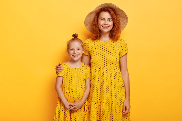 父母工作室拍摄的红头发的母亲和女儿在类似的服装摆姿势生姜裙子童年