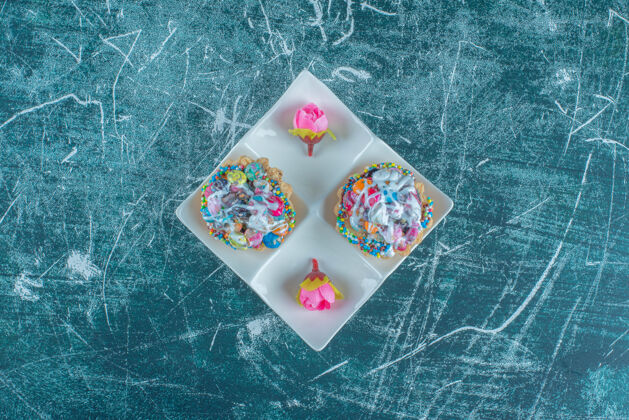 糖果蓝色背景上有杯形蛋糕和花冠的盘子高质量照片牙刷甜点甜品