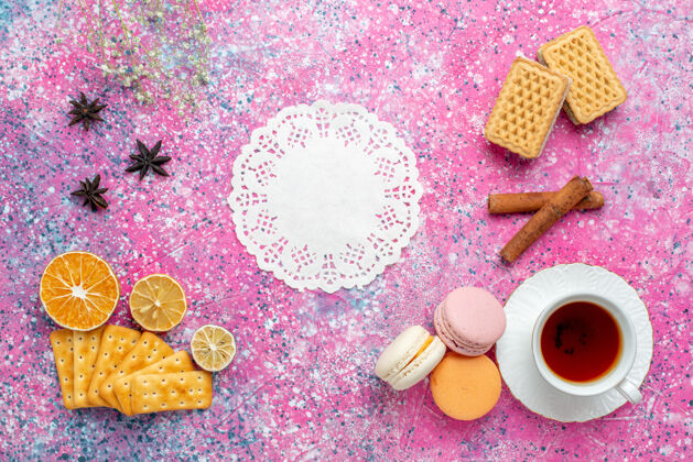 法国在浅粉色的桌子上 可以俯瞰一杯茶 里面放着法国马卡龙和饼干图案杯子顶部