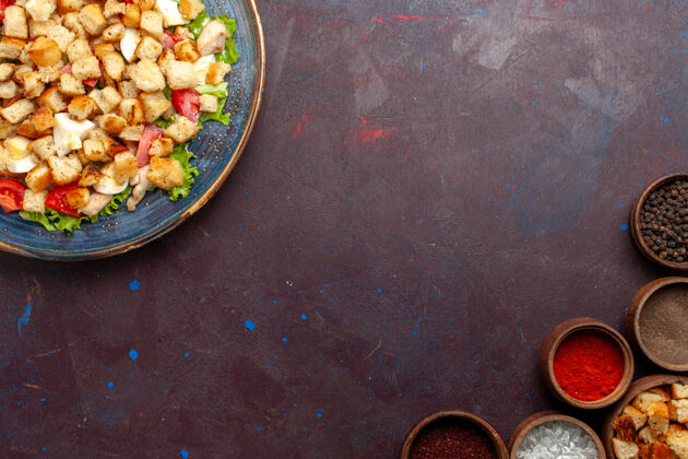 顶在黑暗的桌子上俯瞰美味的凯撒沙拉和不同的调味品盘子沙拉餐