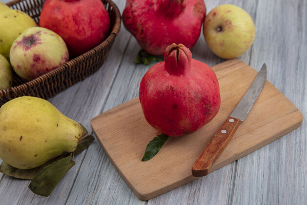 食品新鲜石榴的顶视图在一个木制的厨房板上 刀子上的苹果和木瓜被隔离在一个灰色的背景上板灰色厨房