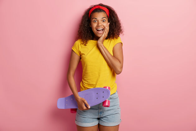 乐观快乐的非洲裔少女握着滑板 一边和朋友玩一边溜冰 享受积极的休息滑板长板青少年