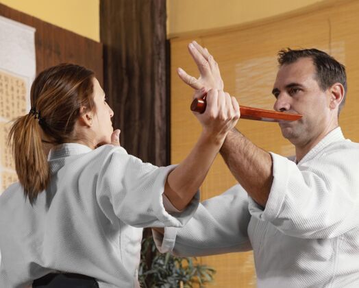 女人男武术教练和女学员在练习厅的侧视图训练男人战斗