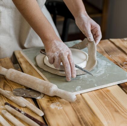 手工有创意的女人在她的工作室里做一个陶罐手工陶工粘土
