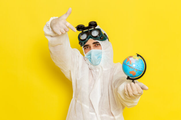 保护套正面图：一位身着特殊套装的男科学工作者手持小圆球在黄色的桌子上摆姿势西装化学前面