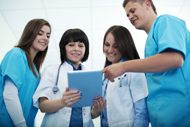 检查医疗队在数字平板电脑上检查结果成熟成人实验服诊所