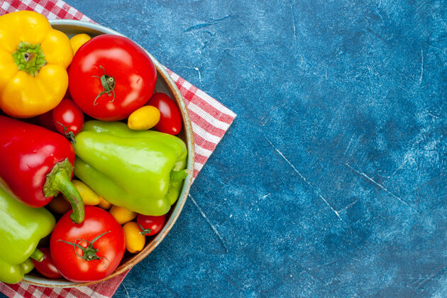 拼盘上半部分查看新鲜蔬菜樱桃西红柿不同颜色甜椒西红柿孜然在盘子上红色和白色格子桌布在蓝色的桌子上与自由空间格子颜色一半