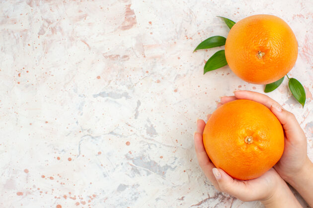 维生素顶视图新鲜橙子在女性手中和明亮的孤立表面与复制空间柑橘顶级光明