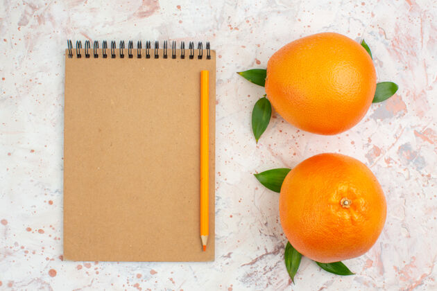 柑橘顶视图新鲜橘子橘子铅笔笔记本上明亮的孤立的表面笔记本新鲜的橘子观点