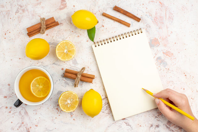 记事本顶视图新鲜柠檬切柠檬肉桂棒一杯柠檬茶铅笔在一个女性手记事本上明亮孤立的表面铅笔削减茶