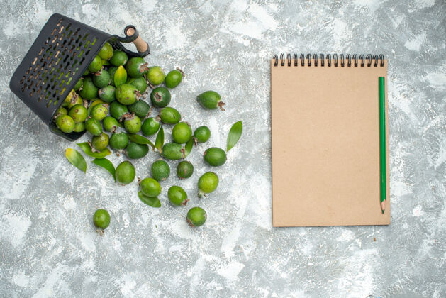 顶部顶视图新鲜的feykhoas分散从篮子笔记本和绿色铅笔在灰色的表面豌豆图钉豌豆