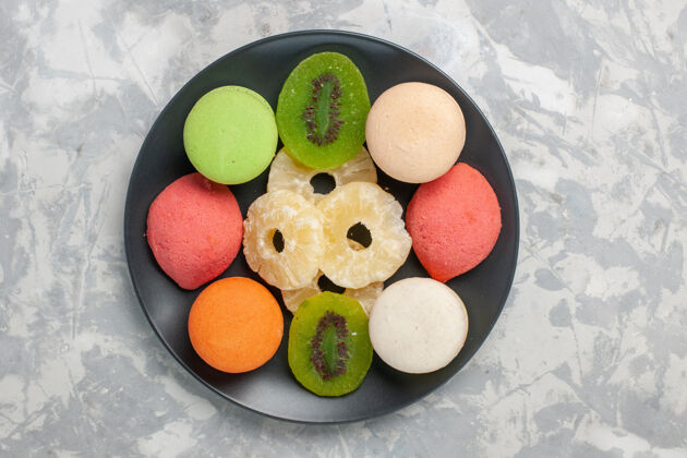 顶顶视图彩色小蛋糕与干菠萝环在浅白色的表面减肥甜饼干