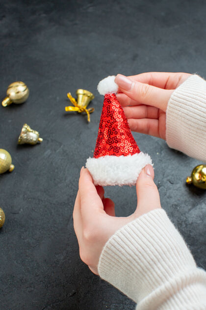 风景手持圣诞老人帽子和装饰配件在黑暗背景下的垂直视图手指圣诞封面