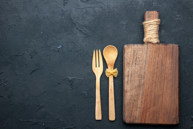叉子顶视图木制服务板木制勺子和叉子在黑暗的桌子上复制空间餐厅餐具服务