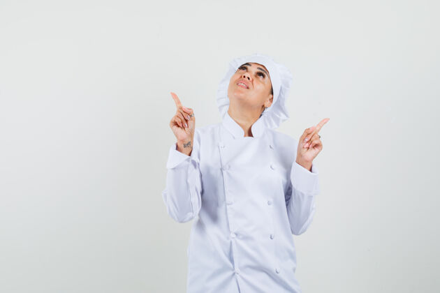 服务一位身穿白色制服的女厨师向上指了指 看上去很专注烹饪集中餐厅