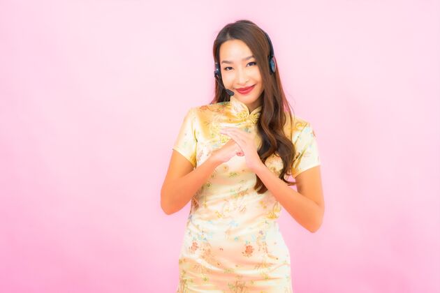 帮助台粉红色墙上的美丽亚洲年轻女性客户呼叫中心护理肖像微笑服务中国人