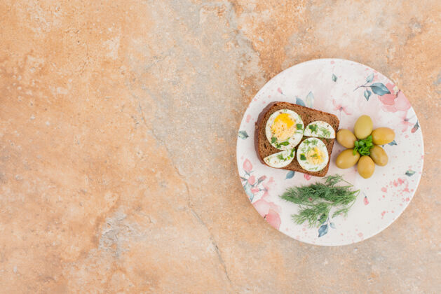 绿色美味的吐司与煮熟的鸡蛋和橄榄在盘子里沸腾橄榄美味