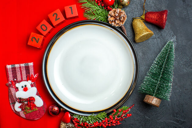 碗新年背景的顶视图与餐盘装饰配件杉木枝和数字在一个红色餐巾旁边的圣诞树在一个黑色的桌子上杉木树枝饮料