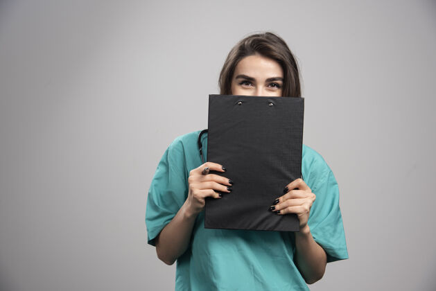 检查穿着制服的女医生躲在剪贴板后面个人健康听诊器