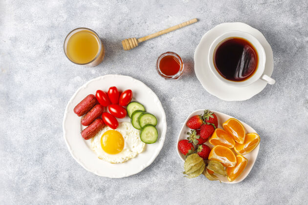 早上早餐盘子里有鸡尾酒香肠 煎蛋 樱桃番茄 糖果 水果和一杯桃子汁鸡蛋视图午餐