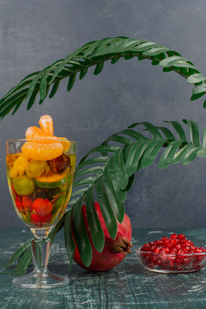 水果大理石桌上放着一杯水果和石榴籽健康种子盘子