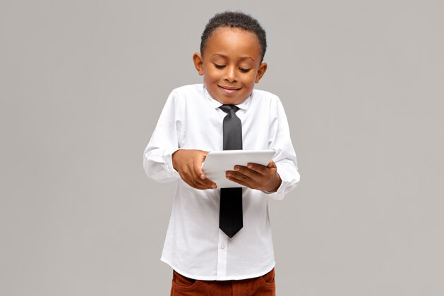 触摸童年时代 现代科技和沉迷可爱的美国黑人小学生沉迷于电子产品使用数字平板电脑玩电子游戏 已经吸收面部表情幸福孩子数码