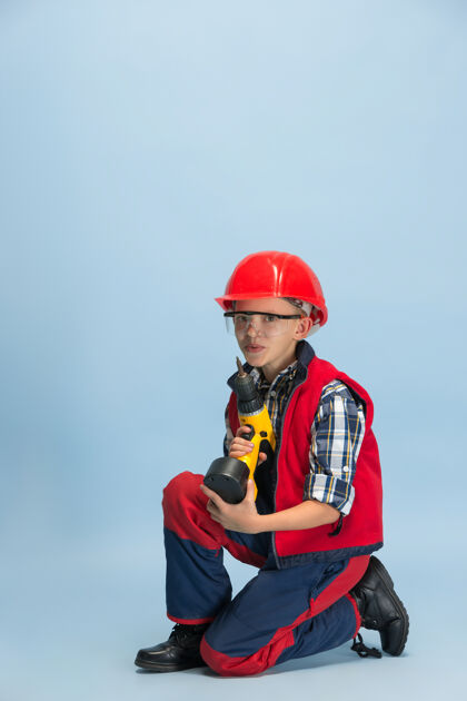 背心戴着红帽拿着电钻的男孩护目镜格子工具
