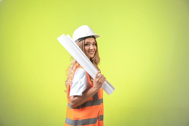 工作戴着头盔和装备的女工程师拿着施工图微笑着自信公司专业