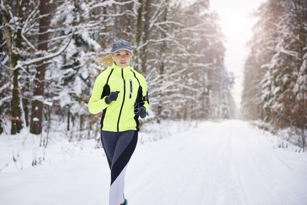 运动员冬日森林里奔跑的女人的正视图健康的生活方式公共严肃