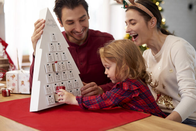 父母一家人带着孩子过圣诞节桌子日历圣诞灯